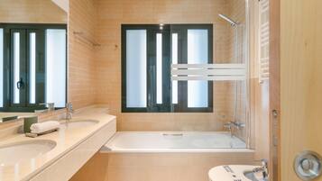 A modern bathroom with a bathtub, a toilet, and a large mirror.