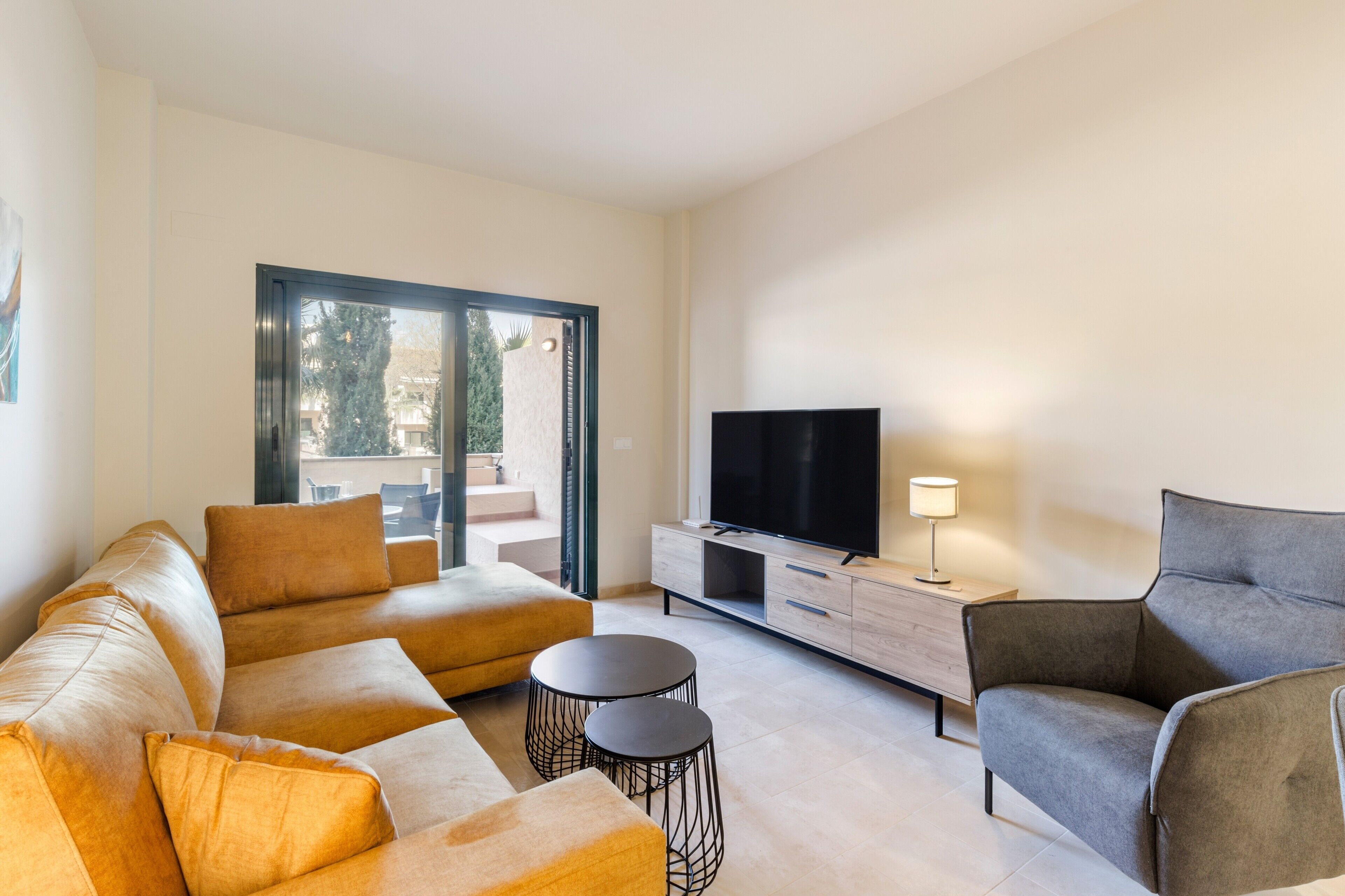 Una sala de estar moderna con un conjunto de sofá, un televisor, una lámpara y una mesita.