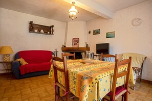 Angolo ristoro con tavolo imbandito per quattro persone, un divano rosso, una televisione e un camino.
