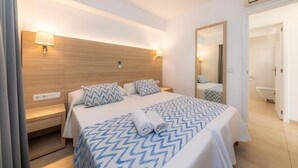 A hotel room with a bed, bedside tables, a mirror, and an air conditioning unit. - Apartment 'Apartamento Bon Aire N1' with Shared Pool, Wi-Fi and Air Conditioning (Cala Ferrera)