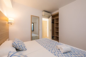 Un dormitorio con una cama, una lámpara de noche, un armario y un espejo.