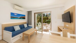 A modern living room with a sofa, a table, a TV, and a sliding glass door leading to an outdoor area. - Apartment 'Apartamento Bon Aire N1' with Shared Pool, Wi-Fi and Air Conditioning (Cala Ferrera)