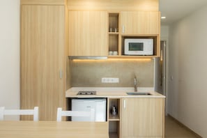 Une cuisine de taille réduite, dotée de meubles en bois, d’un four à micro-ondes, d’un évier et d’un lave-vaisselle.