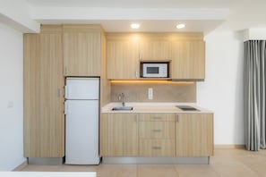 A modern kitchen with wooden cabinets, a built-in microwave, a refrigerator, and a sink.