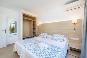 Une chambre d’hôtel équipée d’un lit, d’une armoire, d’une table de chevet, d’une lampe et d’un appareil de climatisation.