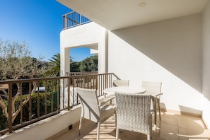A balcony with wicker furniture, a railing, and a view of the surrounding area.