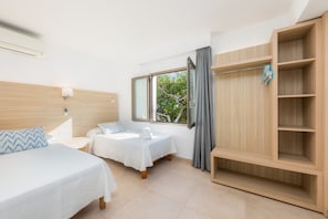Une chambre d’hôtel avec un lit, un petit bureau, une fenêtre avec des rideaux et une armoire en bois.