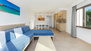 A modern living room with a sofa, a dining table, and a kitchen area. - Apartment 'Aquamarina 7' with Shared Pool, Wi-Fi and Air Conditioning (Cala Ferrera)
