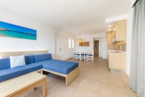 Un salon moderne comprenant un canapé, une table basse et un coin repas avec des chaises et une table.