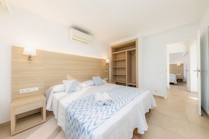 Een hotelkamer met een bed, nachtkastje, wandgemonteerde airconditioning en een kledingkast.