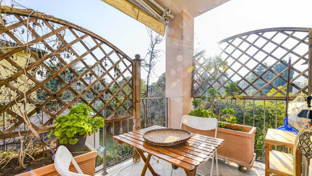 A balcony with a wooden table, chairs, potted plants, and a lattice structure. - Apartment 'In The Center Of Salò' with Balcony, Wi-Fi and Air Conditioning (Salò)