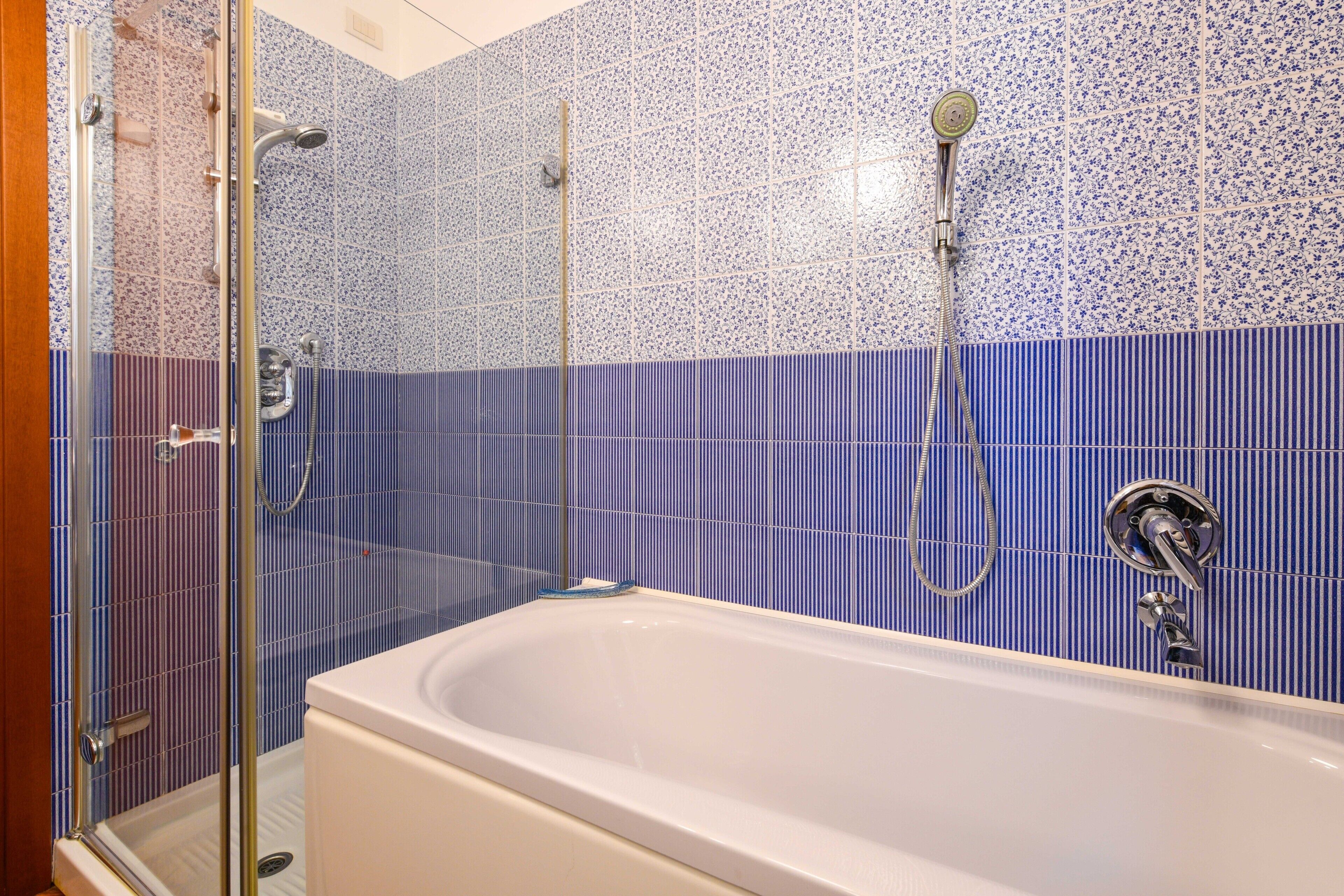 Ein Badezimmer mit Badewanne, Dusche und Fliesenwänden.