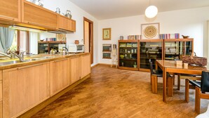 A kitchen with wooden cabinets, a dining table with chairs, a microwave, and a hanging light fixture. - Apartment 'In The Center Of Salò' with Balcony, Wi-Fi and Air Conditioning (Salò)