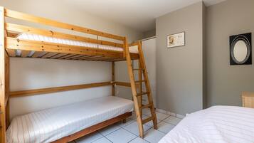 A bunk bed room with a ladder, a small bedside table, and a framed picture on the wall.