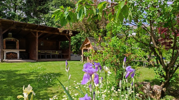 Un giardino fiorito con un edificio rustico dotato di camino.