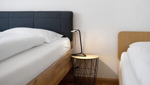 Una camera da letto con due letti, un tavolino rotondo e una presa elettrica a muro.
