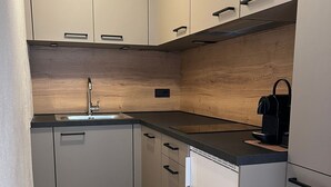 Una cucina compatta con soffitto in legno, un lavello, una macchina da caffè e una lavastoviglie.