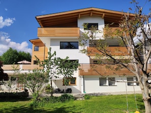 Un immeuble résidentiel moderne à plusieurs étages, doté d’un toit plat, de grandes fenêtres et d’éléments décoratifs en bois.