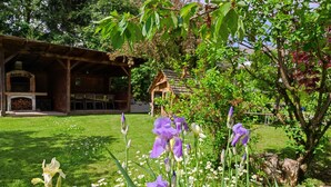 A garden with flowers and a rustic building with a fireplace.