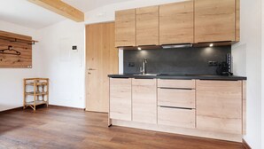 A modern kitchen with wooden cabinets, a black countertop, and a built-in stove. - Holiday Apartment "Haus Mader 1" with Mountain View, Private Terrace & Wi-Fi (Riscone Brunico)