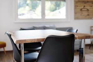 A dining table with chairs, a window with a view, and a wooden wall decoration.
