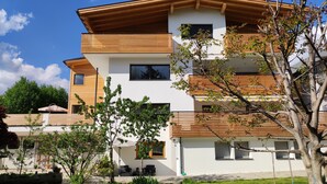 A modern multi-story residential building with a flat roof, large windows, and a well-maintained lawn. - Holiday Apartment "Haus Mader 1" with Mountain View, Private Terrace & Wi-Fi (Riscone Brunico)