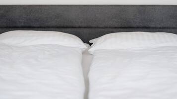 Ein Bett mit weißer Bettwäsche und einem grauen Kopfteil.