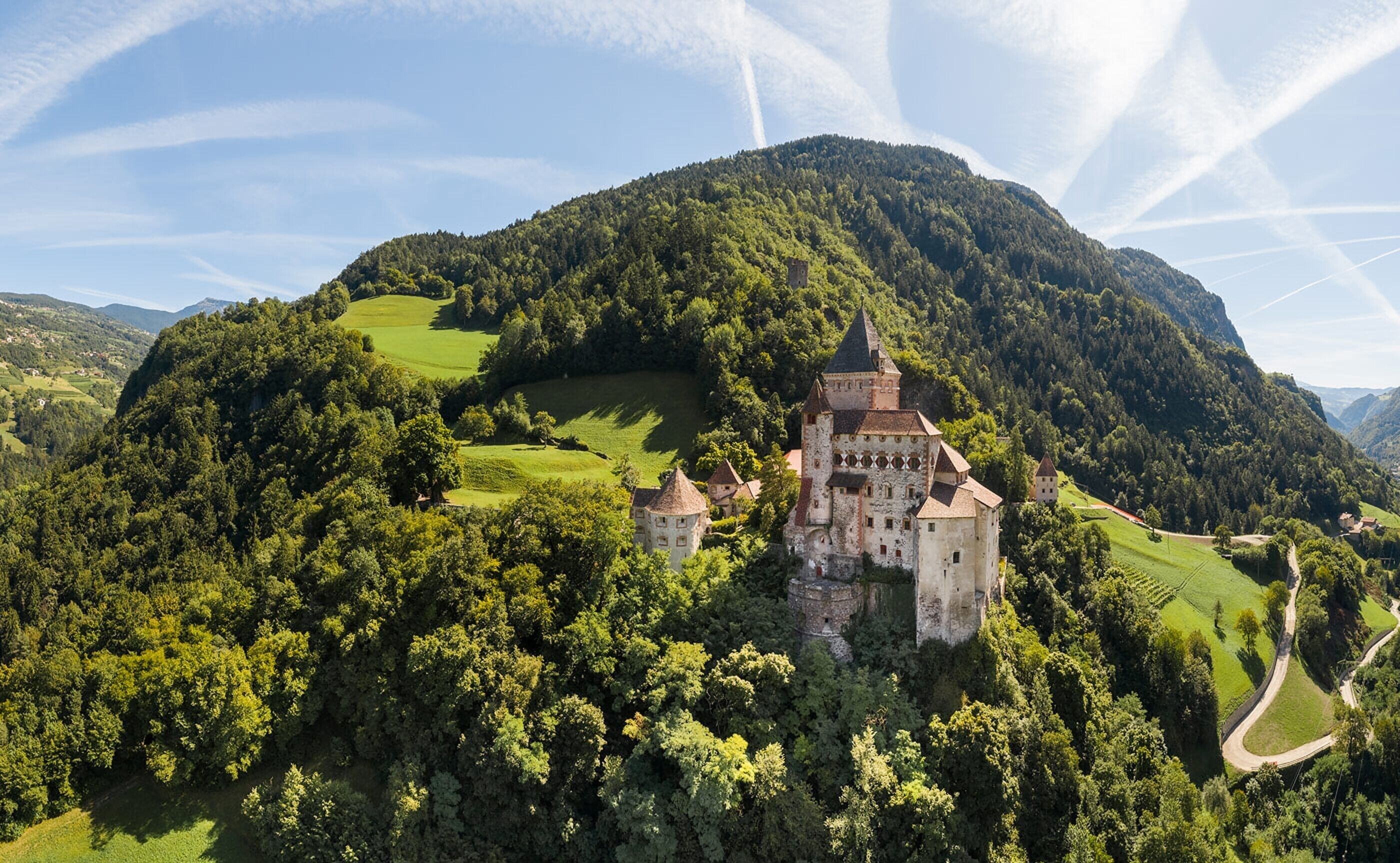 A castle surrounded by lush greenery and hills.