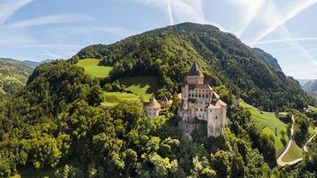 A castle surrounded by lush greenery and hills.