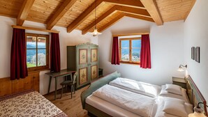 Une chambre avec un plafond en bois, un lit, un bureau et une vue sur les montagnes.