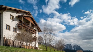Un bâtiment blanc doté de balcons en bois, avec une chaîne de montagnes en arrière-plan.