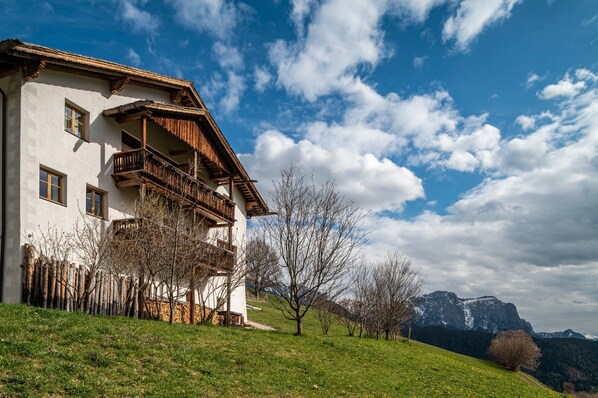 A white building with wooden balconies and a mountain backdrop.