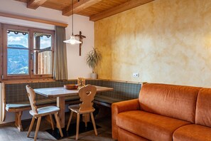 Een gezellige kamer met een houten tafel, twee stoelen, een bankje en een sofa.