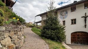 A cobblestone path leading to a building with a wooden balcony and a mural. - Apartment 'Biohof Maurer Apt Vogelstimmen' with Mountain View, Shared Garden and Wi-Fi (Laion)