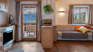 A kitchen with wooden cabinets, a stove, and a window with a view of mountains. - Apartment 'Biohof Maurer Apt Vogelstimmen' with Mountain View, Shared Garden and Wi-Fi (Laion)
