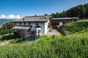 A house with a large glass enclosure, a balcony, and a solar panel array.
