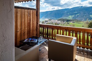 Eine Holzterrasse mit Tisch und Stühlen, mit Blick auf eine Berglandschaft.
