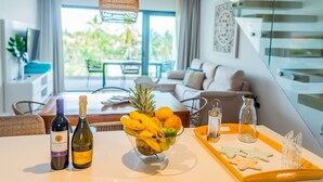 A dining area with a table set for two, featuring a fruit bowl, two bottles of wine, and a tray with star-shaped cookies.