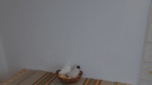 Un mueble de madera con cajones, una cesta tejida con toallas y un cuadro enmarcado en la pared.