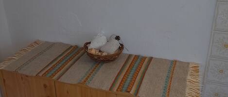 Un mueble de madera con cajones, una cesta tejida con toallas y un cuadro enmarcado en la pared.