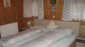 Una cama doble con ropa de cama estampado de estrellas, paredes de paneles de madera y una mesita de noche pequeña con una lámpara.