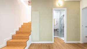 A staircase with wooden steps leading to a room with a light-colored wall and a door leading to a bathroom.