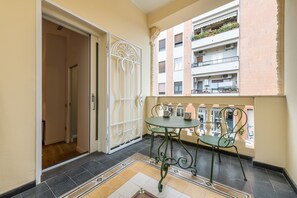 Un balcón con una mesa y sillas, un enrejado decorativo y vistas a un edificio con balcones.