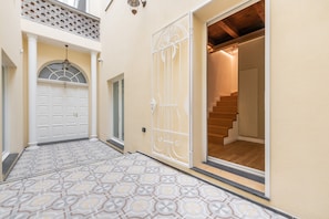Un pasillo con baldosas de diseño, una puerta blanca y una escalera que sube a un nivel superior.