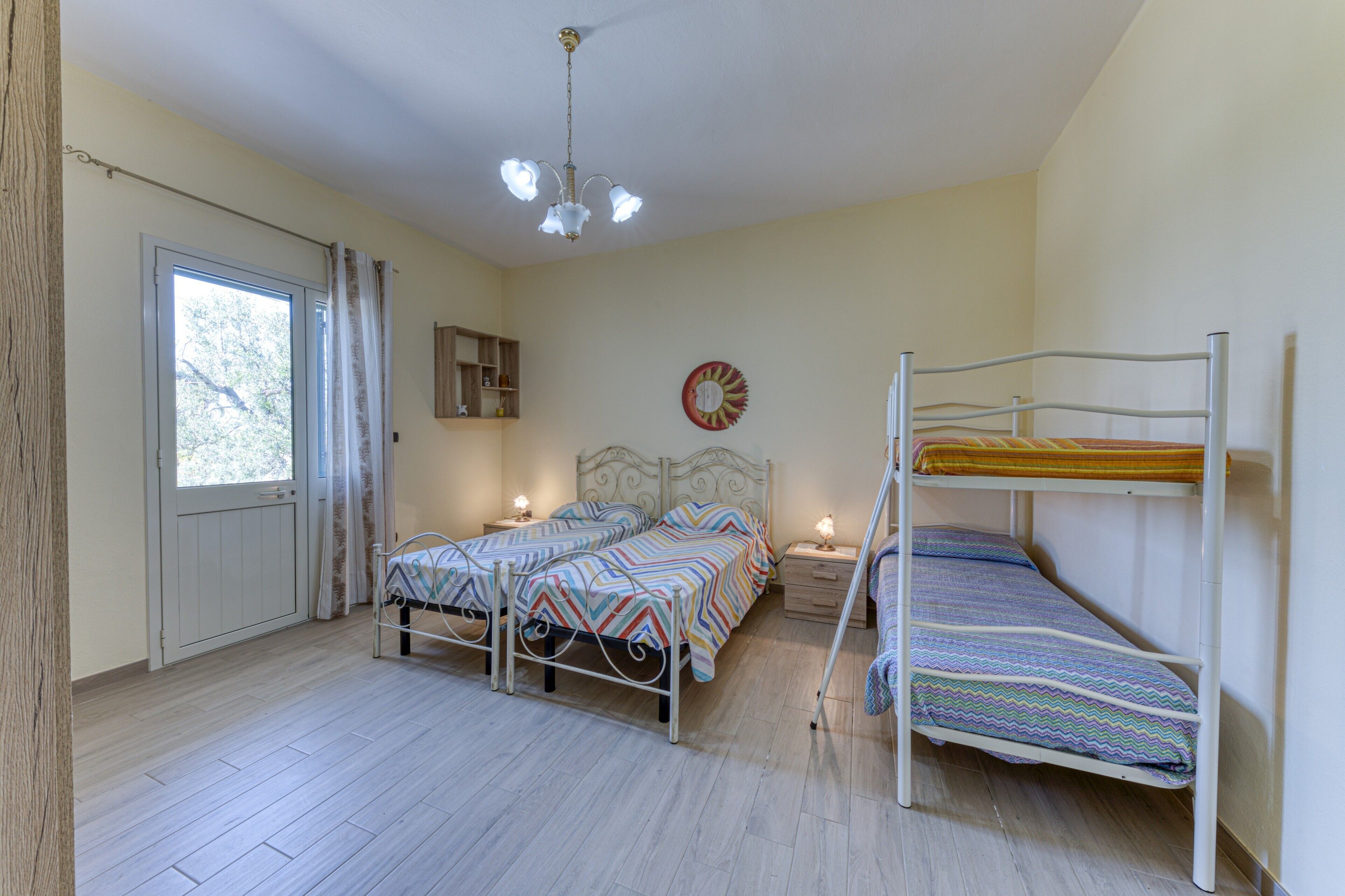 Camera da letto con due letti, una finestra, una porta, una ventola a soffitto e un orologio a muro.