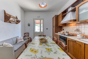 Una cocina con armarios de madera, una mesa de comedor con mantel de girasol y un horno empotrado.