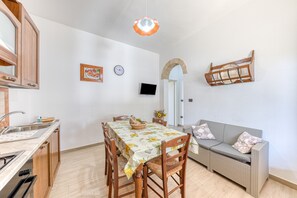 Un comedor con una mesa, sillas, un sofá, un televisor y un reloj en la pared.