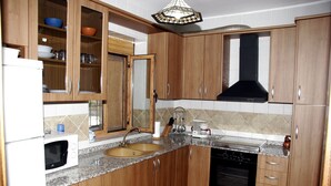 A kitchen with wooden cabinets, a double sink, a microwave, a stove, and a dishwasher. - Holiday Home 'Rural Fábrica Del Azúcar 2' with Mountain View, Wi-Fi and Air Conditioning (Pozo Alcon)