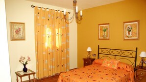 A bedroom with a bed, curtains, a nightstand, a lamp, and a vase with flowers. - Holiday Home 'Rural Fábrica Del Azúcar 2' with Mountain View, Wi-Fi and Air Conditioning (Pozo Alcon)