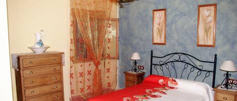 A bedroom with a bed, wooden dresser, nightstands, and a chandelier.
